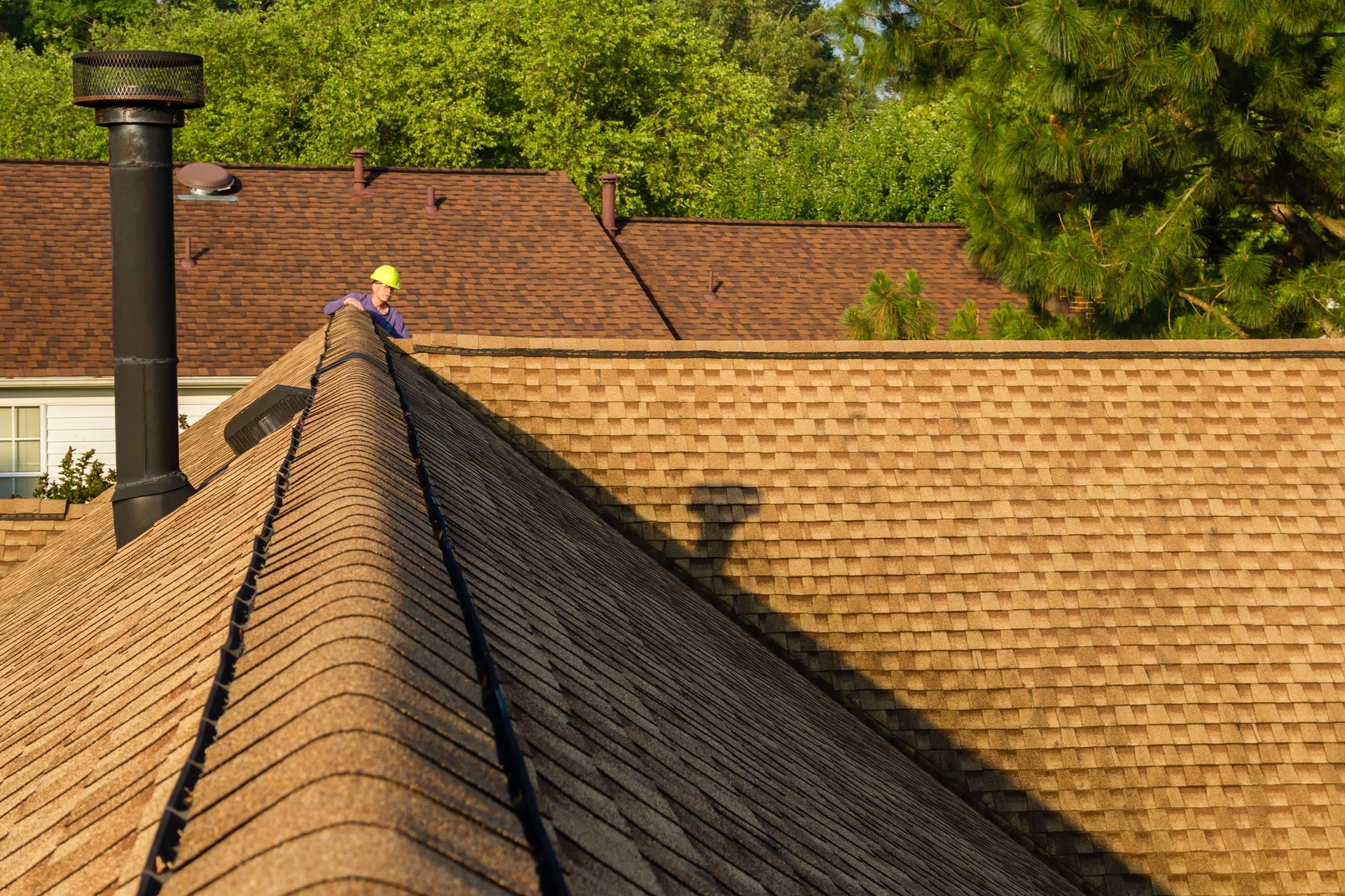 Home inspector examines architectural, asphalt shingled roof.
